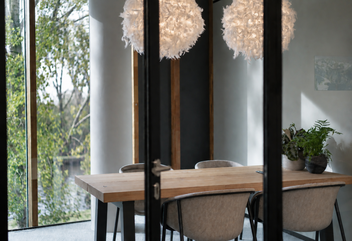 Moderne vergaderruimte met massief houten vergadertafel, sfeerverlichting en uitzicht op het groen binnen het zakelijke interieurontwerp voor ChaletsPlus.