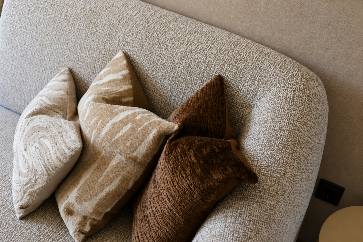 Detail van luxe bank met design sierkussens in warm en modern interieur Schipluiden