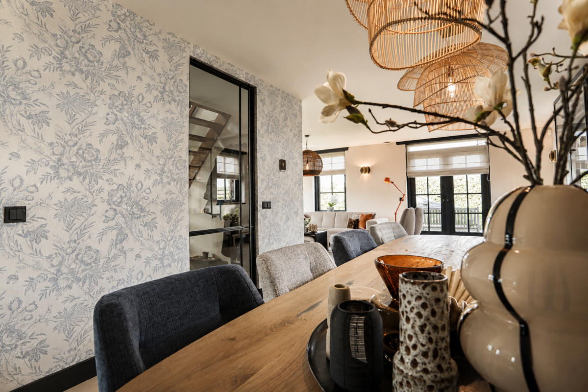Eetkamer met houten eettafel, comfortabele eetkamerstoelen en sfeervolle verlichting in een modern landelijk interieur