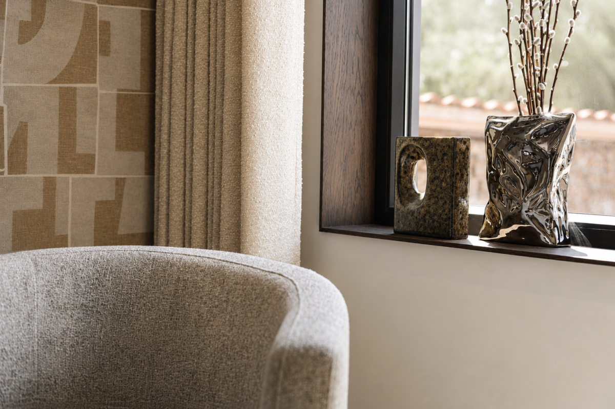 Luxe fauteuil bij raam met stijlvolle raamdecoratie en designaccessoires in woning Schipluiden