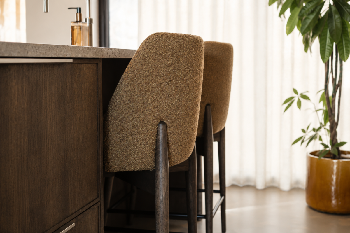 Donkere maatwerk keuken met gestoffeerde barstoelen en luxe afwerking in woning Schipluiden