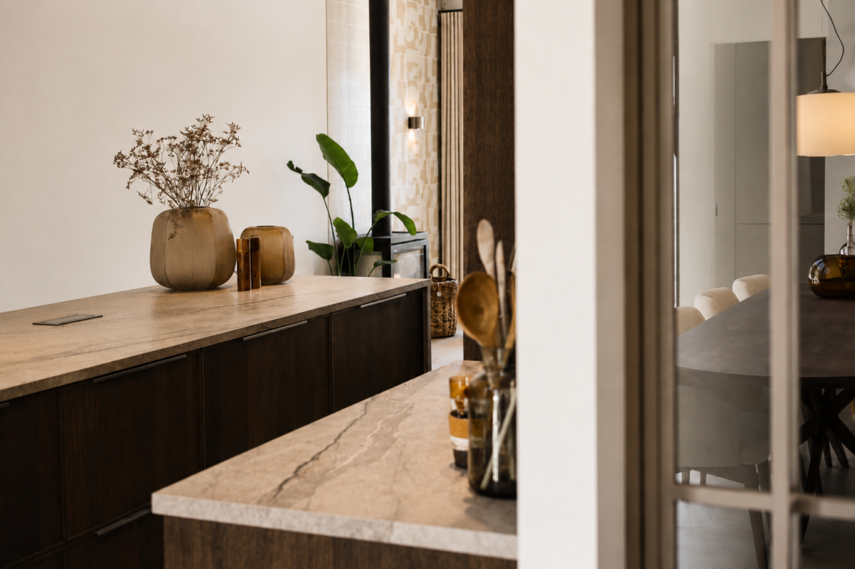 Maatwerk keuken met natuurstenen werkblad en donkere houtafwerking in vrijstaande woning Schipluiden
