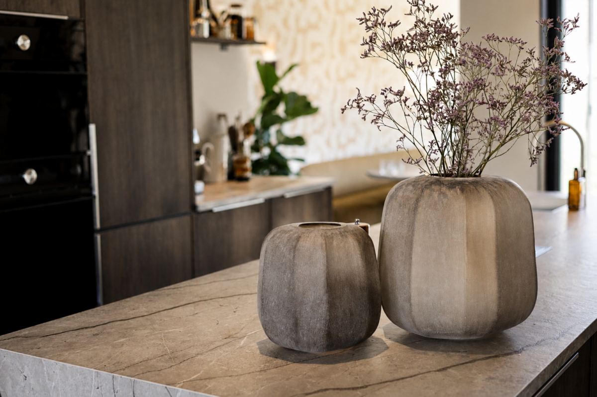 Keukeneiland met natuurstenen werkblad en stijlvolle woonaccessoires in luxe woning Schipluiden