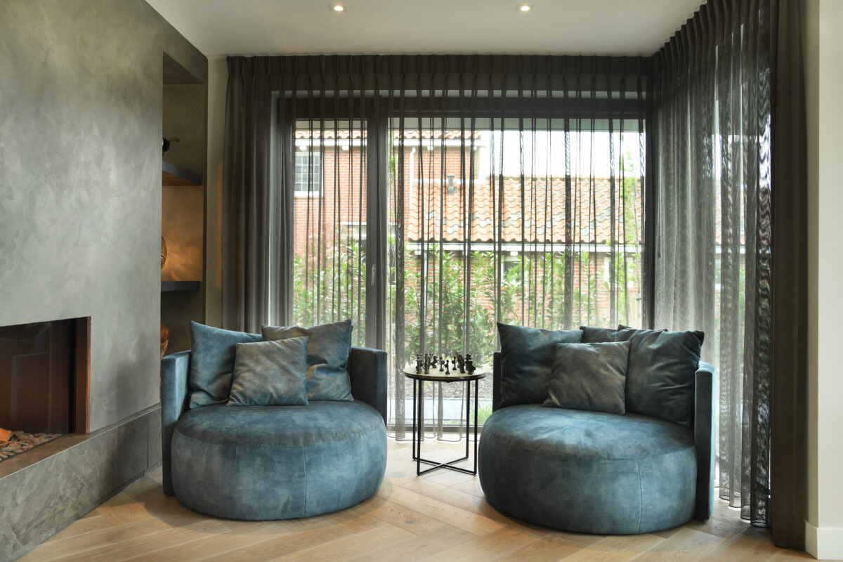 Sfeervolle zithoek met design fauteuils en doorkijk naar de moderne haard