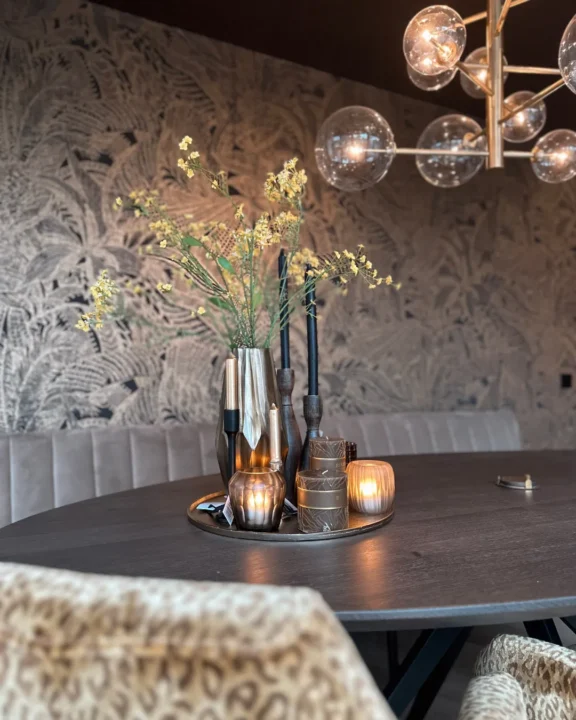 Gestylede eethoek met ronde tafel, botanisch behang en bollen hanglamp